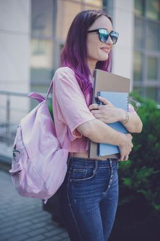 Portrait beautiful female writer dressed in casual outfit holding modern laptop in hand with backpack. Young student of faculty journalism having good mood outdoor