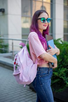 Portrait beautiful female writer dressed in casual outfit holding modern laptop in hand with backpack. Young student of faculty journalism having good mood outdoor