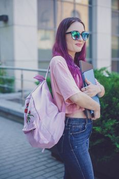 Portrait beautiful female writer dressed in casual outfit holding modern laptop in hand with backpack. Young student of faculty journalism having good mood outdoor