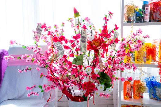 A holiday tree with red and pink knuckles decorated with 100 dollar bills. Ukrainian wedding branch at a gypsy wedding. Ukraine, Vinnytsia, August 10, 2021