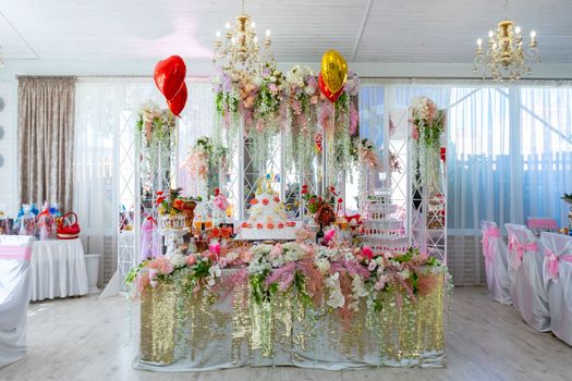 The wedding table of the bride and groom is decorated with many different flowers. A big cake on the bride's table. Ukraine, Vinnytsia, August 10, 2021.
