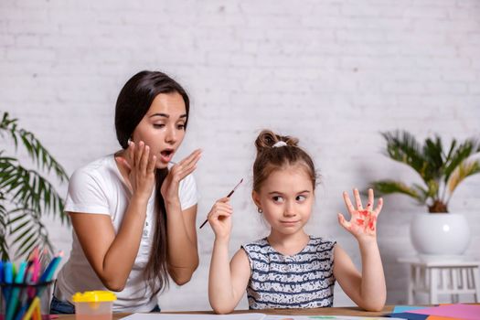 Happy family. Mother and daughter together paint. Woman helps the child girl.