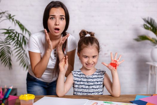 Happy family. Mother and daughter together paint. Woman helps the child girl.