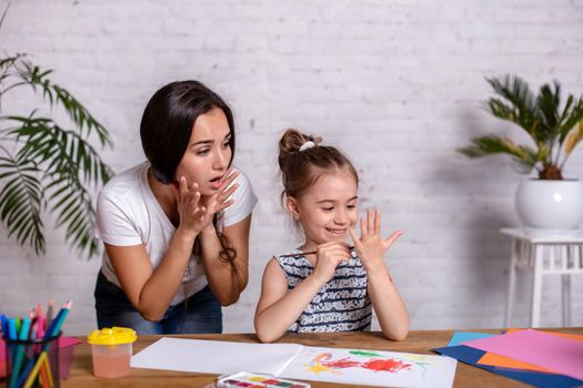 Happy family. Mother and daughter together paint. Woman helps the child girl.