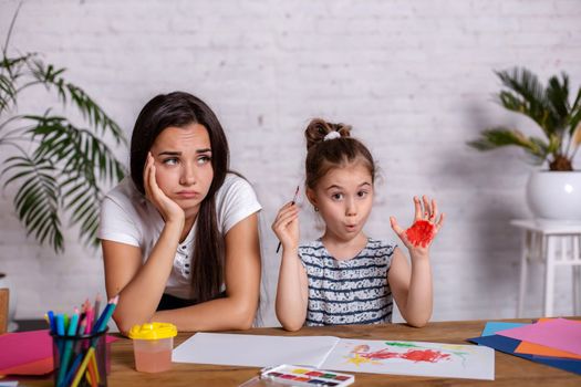 Happy family. Mother and daughter together paint. Woman helps the child girl.