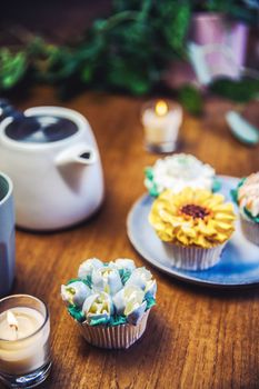 Various cupcakes decorated with colorful flower icing on wooden table, floral bouquet, wedding cake, High tea, Holiday concept Mothers day