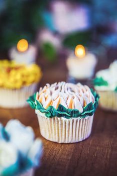 Various cupcakes decorated with colorful flower icing on wooden table, floral bouquet, wedding cake, High tea, Holiday concept Mothers day