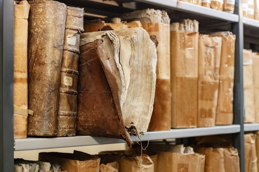 Old worn 17th century books on a shelf in the library's archives