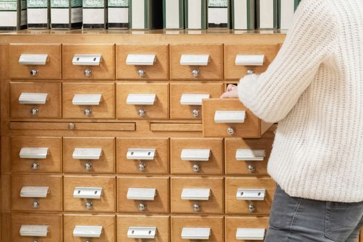 Librarian hand opens library card or file catalog box.