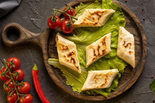 Delicious fried pita bread roll with cottage cheese and herbs. Fried puff rolls of thin Armenian lavash stuffed with cottage cheese. Wrapped tortillas. View from above.