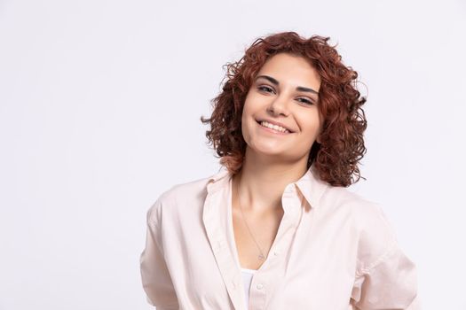 Sincere smile of a young European woman. Attractive girl with short chestnut-colored hair. Naturally curly hair.
