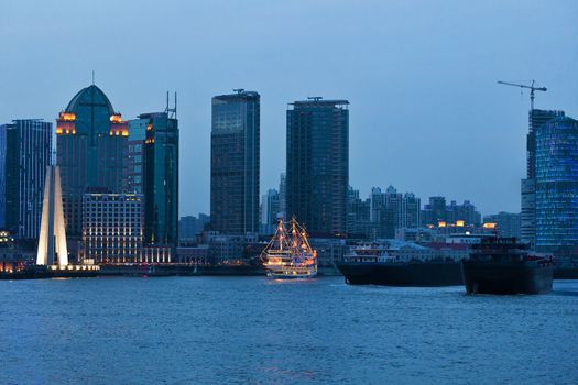 Shanghai skyscrapers near water at night with mirror