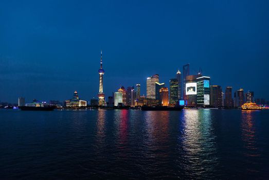 Shanghai skyscrapers near water at night with mirror