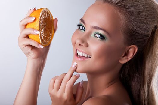 Beautiful young woman smile and squeeze orange