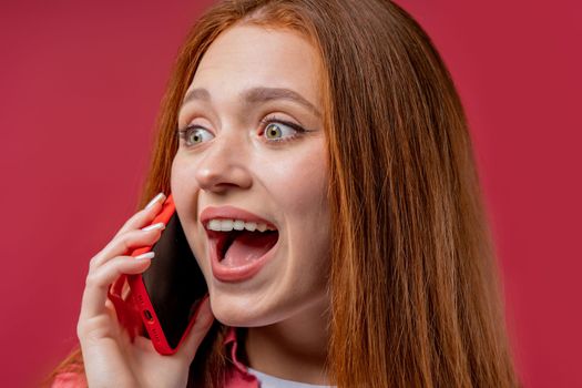 Surprised woman talking by phone, great news, open mouth, wow. Young lady on pink background. Having smartphone call. . High quality photo