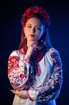 Ukrainian pretty woman in traditional necklaces and embroidered ethnic blouse at blue smoke background. Ukraine, style, folk, culture. High quality photo