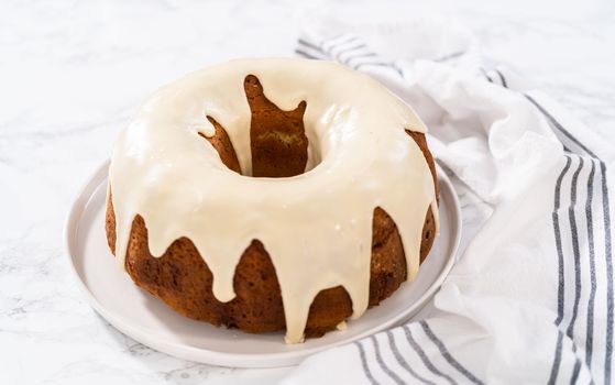 Slicing homemade eggnog bundt cake with an eggnog glaze.