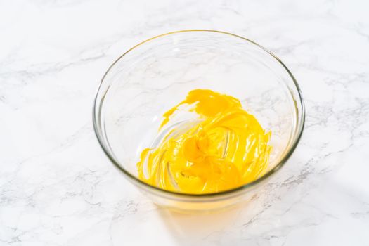Mixing yellow food coloring into the meringue to bake Easter meringue cookies.