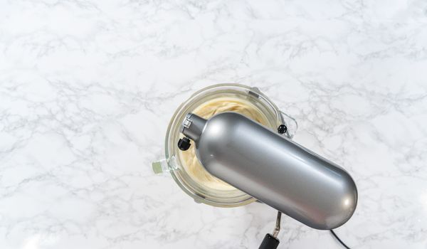 Flat lay. Whipping white ganache in kitchen mixer to make the white chocolate ganache frosting.