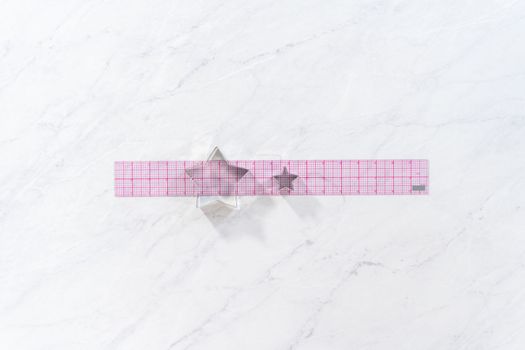 Flat lay. Star-shaped cookie cutters next to the ruler on the kitchen counter.