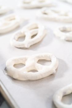 Dipping pretzels twists into melted chocolate to make chocolate-covered pretzel twists.