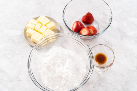 Ingredients in a glass mixing bowls to prepare the strawberry buttercream frosting.