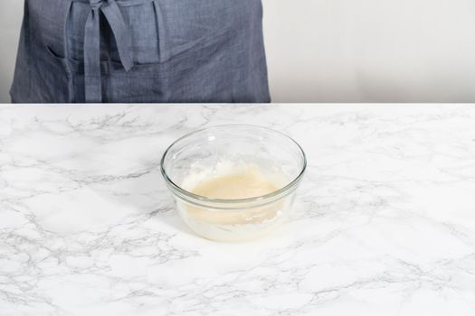 Mixing ingredients with a hand whisk to make eggnog glaze.