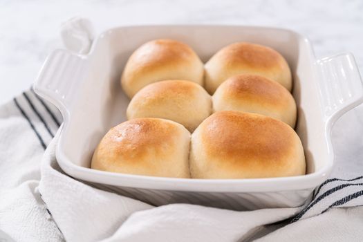 Freshly baked dinner rolls in a white ceramic dish.