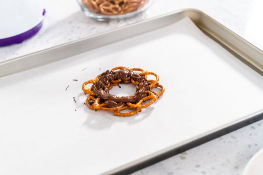 Dipping pretzels twists into melted chocolate to make a chocolate pretzel Christmas wreath.