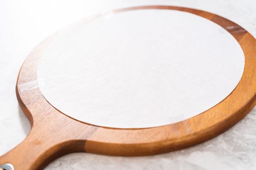 Assembling butter board with vegetables and bread on a round wood cutting board.