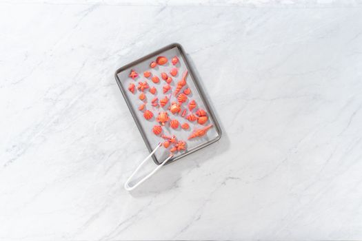 Flat lay. Painting sea-shaped chocolates with glittery luster to decorate chocolate-dipped pretzels twists.
