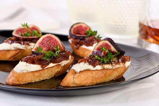 Set Bruschettas with figs and cheese, onion jam, fresh thyme, on grilled crusty bread. Perfect as an aperitif for a holiday or party. 