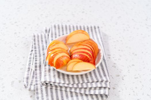 Thinly sliced red apples on a white plate.