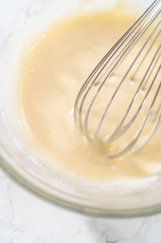 Mixing ingredients with a hand whisk to make eggnog glaze.