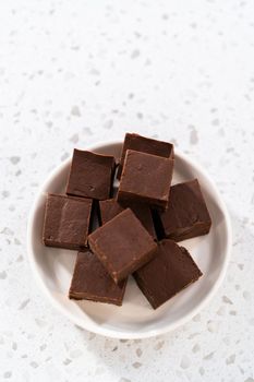 Homemade plain fudge pieces on a white ceramic plate.
