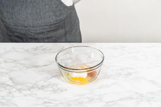Mixing wet ingredients in a small glass mixing bowl to bake mini vanilla cupcakes with ombre pink buttercream frosting.