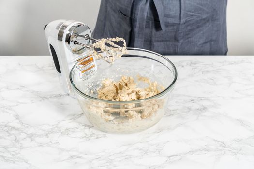 Mixing ingredients with a hand mixer in a large mixing bowl to bake eggnog bundt cake.