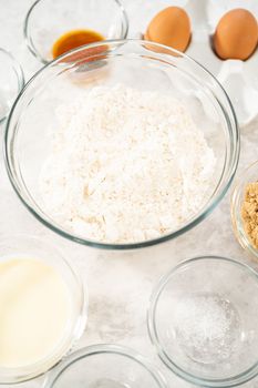 Measured ingredients in glass mixing bowls to bake eggnog scones.