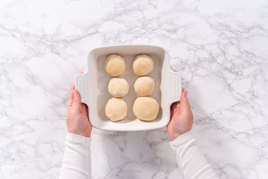 Flat lay. Rising dough in a white ceramic dish to prepare dinner rolls.