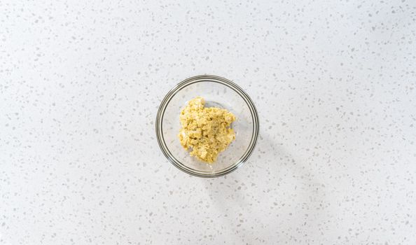 Flat lay. Mixing ingredients in a glass mixing bowl to prepare filling for breakfast empanadas with eggs and sweet potato.