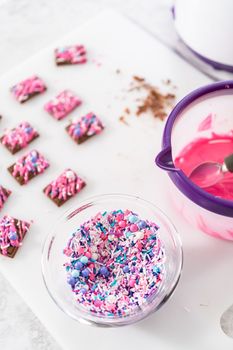 Drizzling melted pink chocolate on top of the mini chocolates and sprinkling some colorful sprinkles on top.