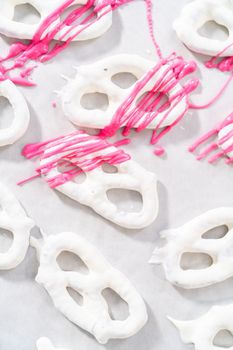 Drizzling melted chocolate over chocolate-dipped pretzels twists.