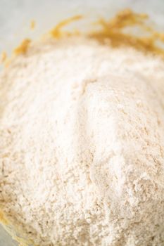 Mixing ingredients in a large glass mixing bowl to bake eggnog scones.