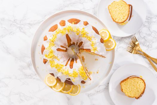 Flat lay. Sliced lemon bundt cake decorated with lemon zest on a cake stand.