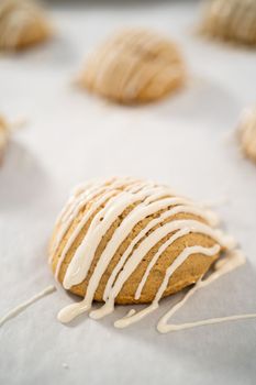 Drizzling melted white chocolate over freshly baked eggnog scones.