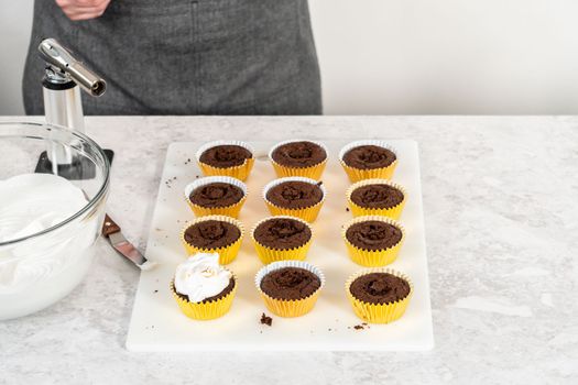 Frosting s'mores cupcakes with white meringue frosting.