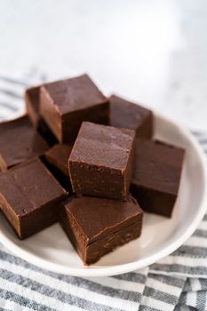 Homemade plain fudge pieces on a white ceramic plate.