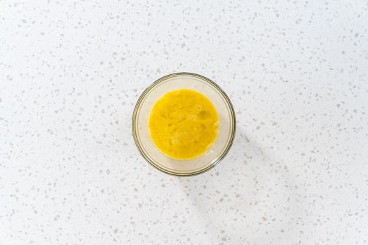 Flat lay. Mixing ingredients in a glass mixing bowl to prepare filling for breakfast empanadas with eggs and sweet potato.