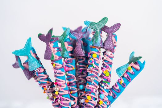 Mermaid chocolate pretzel rods drizzled with pink and purple chocolate and covered with sprinkles.