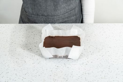 Cutting plain homemade fudge into small pieces on a white cutting board.
